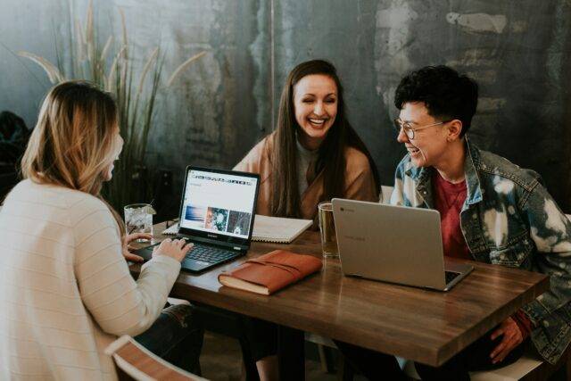 Group of university students studying and laughing in a cafe