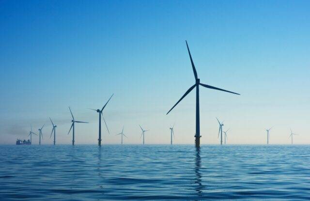 Offshore wind farm with multiple turbines rising from a calm sea under a clear blue sky